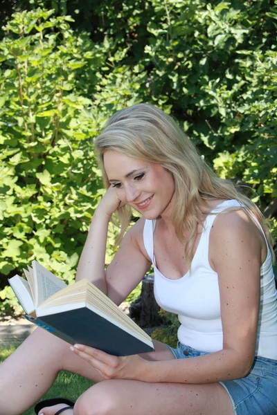 Jonge vrouw lezen in de tuin — Stockfoto