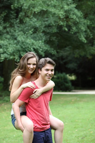 Adolescente menino dando a sua namorada um piggyback — Fotografia de Stock