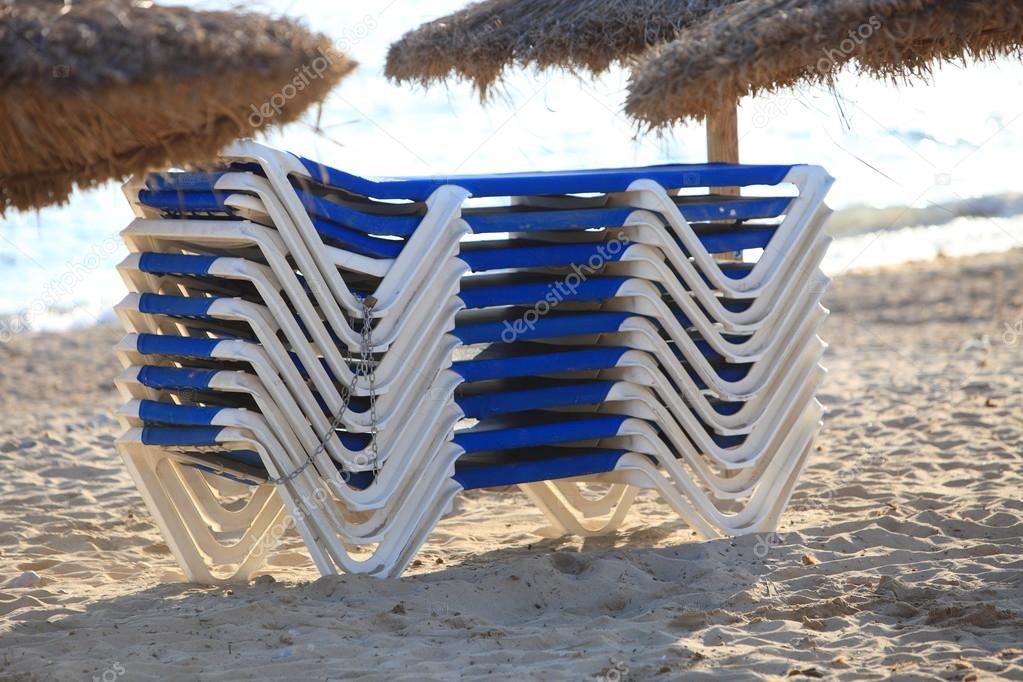 Stack of recliner chairs on a beach