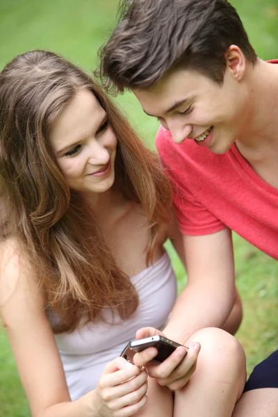 Sonriendo jóvenes adolescentes usando un móvil —  Fotos de Stock