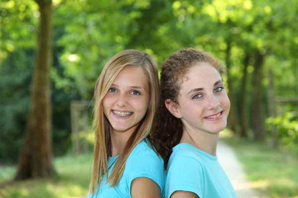 Twee gelukkige tieners permanent samen in een park — Stockfoto