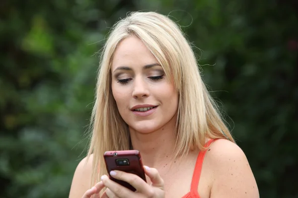 Mulher atraente lendo um sms em seu celular — Fotografia de Stock