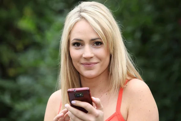Lachende blonde vrouw met een mobiele telefoon — Stockfoto