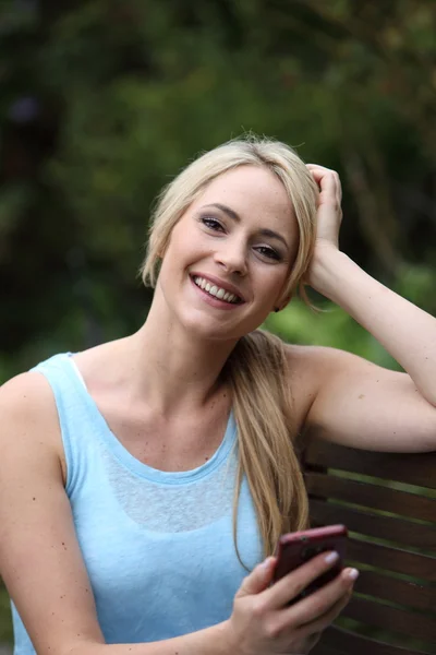 Mooie vrouw lachen op een tuin bankje — Stockfoto