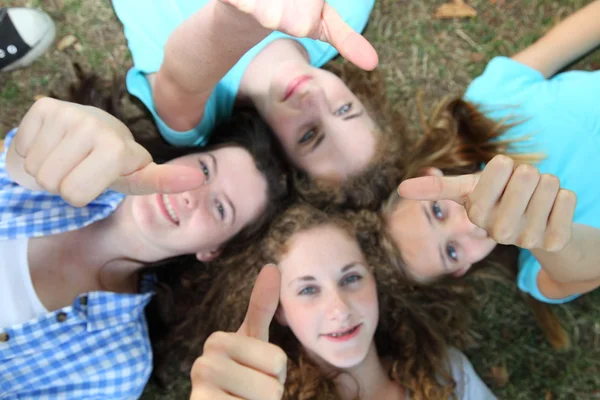 Quatro adolescentes felizes dando polegares ups — Fotografia de Stock
