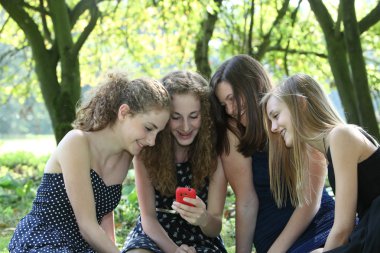 Group of happy teenagers reading an sms clipart