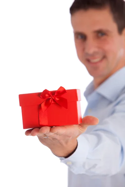 Hombre sonriente ofreciendo un regalo en una caja roja y un arco —  Fotos de Stock