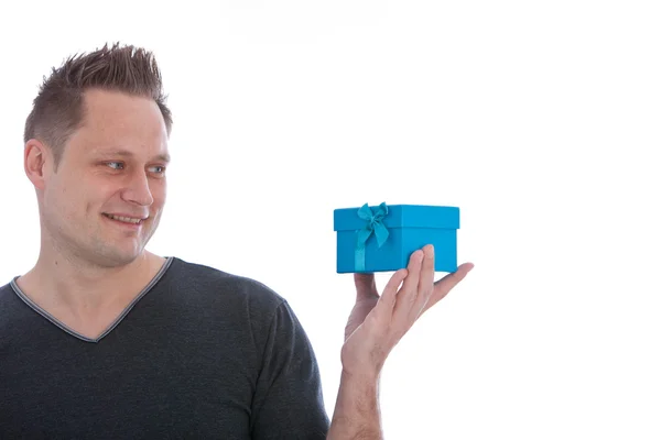 Handsome man eyeing a blue gift box — Stock Photo, Image