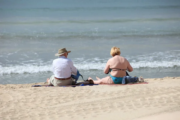 Elderly couple sitting on the beach — Stock Photo, Image