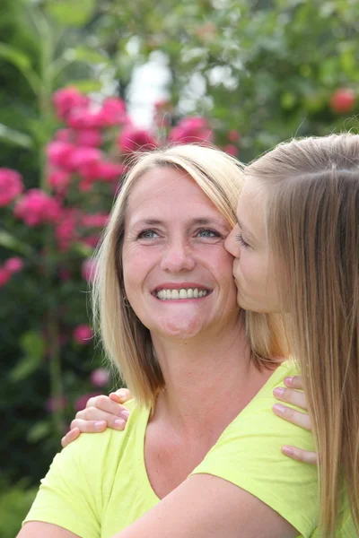 Любящая дочь-подросток целует свою улыбающуюся мать — стоковое фото