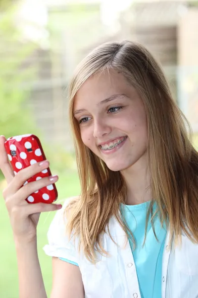 Menina adolescente lendo uma mensagem de texto em seu telefone — Fotografia de Stock