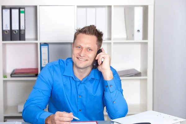 Ung affärsman prata telefon, vid sitt skrivbord — Stockfoto