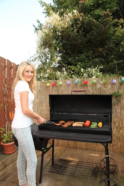 Mujer joven cocinando en una barbacoa al aire libre — Foto de Stock