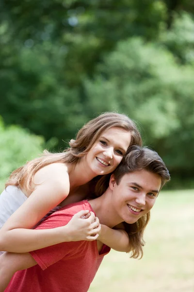 Joven hombre dando a su novia un cerdito espalda —  Fotos de Stock