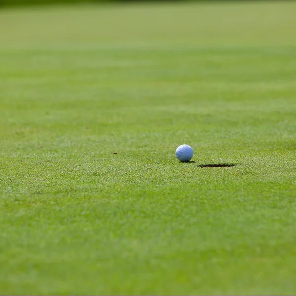 Golfboll ligger på kanten av koppen på hålet — Stockfoto