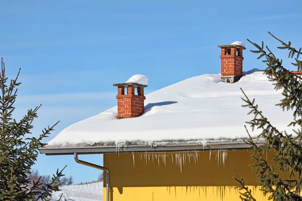 Rode schoorstenen op besneeuwde dak. Piemonte, Italië. — Stockfoto