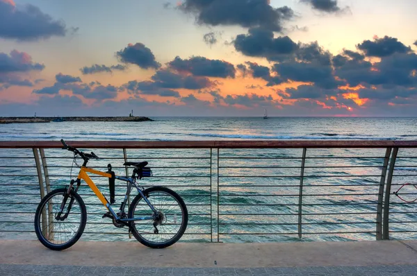 Bicicleta en el paseo marítimo contra el fondo del cielo y el mar puesta del sol . —  Fotos de Stock