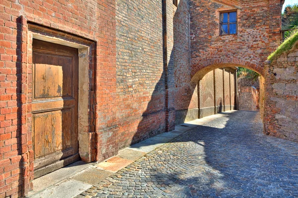 Kopfsteinpflasterstraße und rote Backsteinmauer in der italienischen Stadt. — Stockfoto