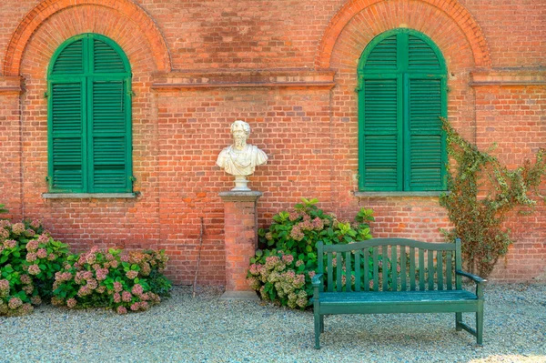 Ξύλινο πάγκο μπροστά από κόκκινο τούβλο σπίτι στην Ιταλία. — Φωτογραφία Αρχείου