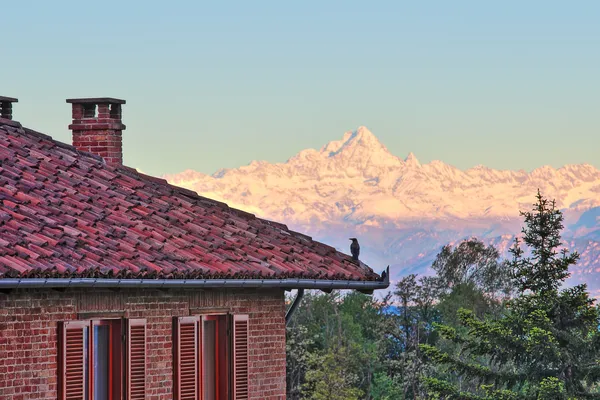 Bakstenen huis en besneeuwde bergen in Italië. — Stockfoto