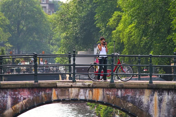 Mujer tomar fotos de pie en el puente en Amsterdam . — Foto de Stock