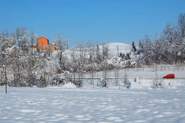 Röd bil och snöiga landskap. — Stockfoto