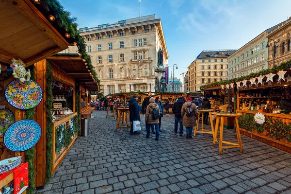 ウィーン オーストリア 2019年12月4日 オーストリアの旧市街で行われている有名な伝統的なクリスマスマーケットで贈り物やお土産を販売する石畳の通りにある木製のキオスクの間を歩く人々 — ストック写真