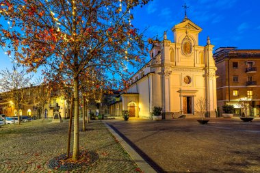 Kasaba meydanındaki Katolik kilisesi ve akşamları Alba, Piedmont, Kuzey İtalya 'da Noel aydınlatmalı ağaçlar..