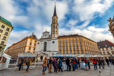VIENNA, AUSTRIA - 05 Aralık 2019: İnsanlar Viyana 'daki ünlü Aziz Michael Kilisesi' nin önündeki küçük kasaba meydanında Noel pazarında alışveriş yapıyorlar - Avusturya 'nın başkenti, popüler turizm beldesi.