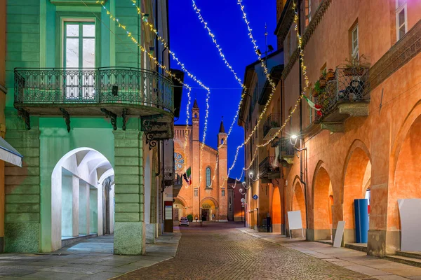 意大利北部皮埃蒙特阿尔巴老城的历史建筑 背景大教堂和圣诞灯饰之间狭窄的鹅卵石街 — 图库照片