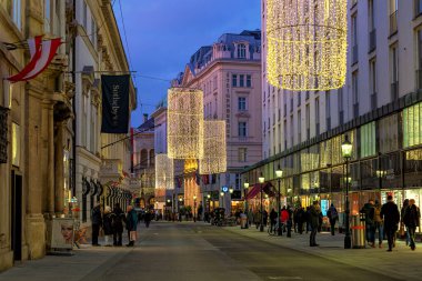 Viyana, AUSTRIA - 04 Aralık 2019: Viyana 'nın merkez caddelerinden birinde yürüyen insanlar akşam saatlerinde Noel tatili için aydınlatılmış ve süslenmiş.