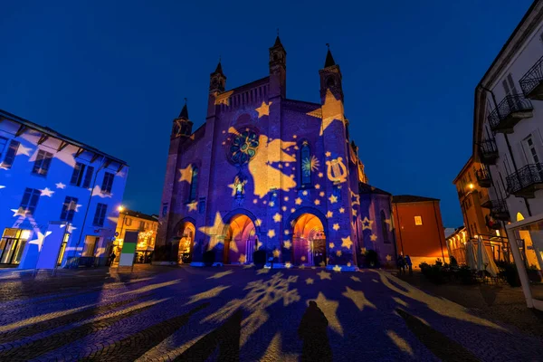 San Lorenzo cathedral illuminated for Christmas holidays in the evening on cobblestone square in old town of Alba, Piedmont, Northern Italy.