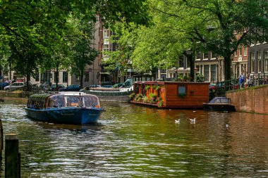 AMSTERDAM, NETHERLANDS - 16 HAZİRAN 2007: Amsterdam 'ın merkezindeki su evinin önünden geçen geleneksel gezi teknesi - başkent, ünlü ve popüler seyahat merkezi.