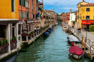 VENICE, İtalya - 20 Nisan 2016: Venedik 'teki eski renkli evler ve tipik cadde boyunca dar kanallarda bulunan teknelerin görüntüsü - adalardaki ünlü İtalyan kasabası, popüler turizm beldesi.
