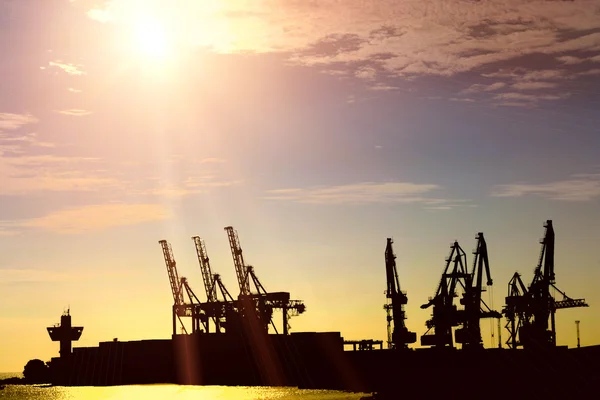 Silhouette of portal cranes in harbor on sunset — Stock Photo, Image