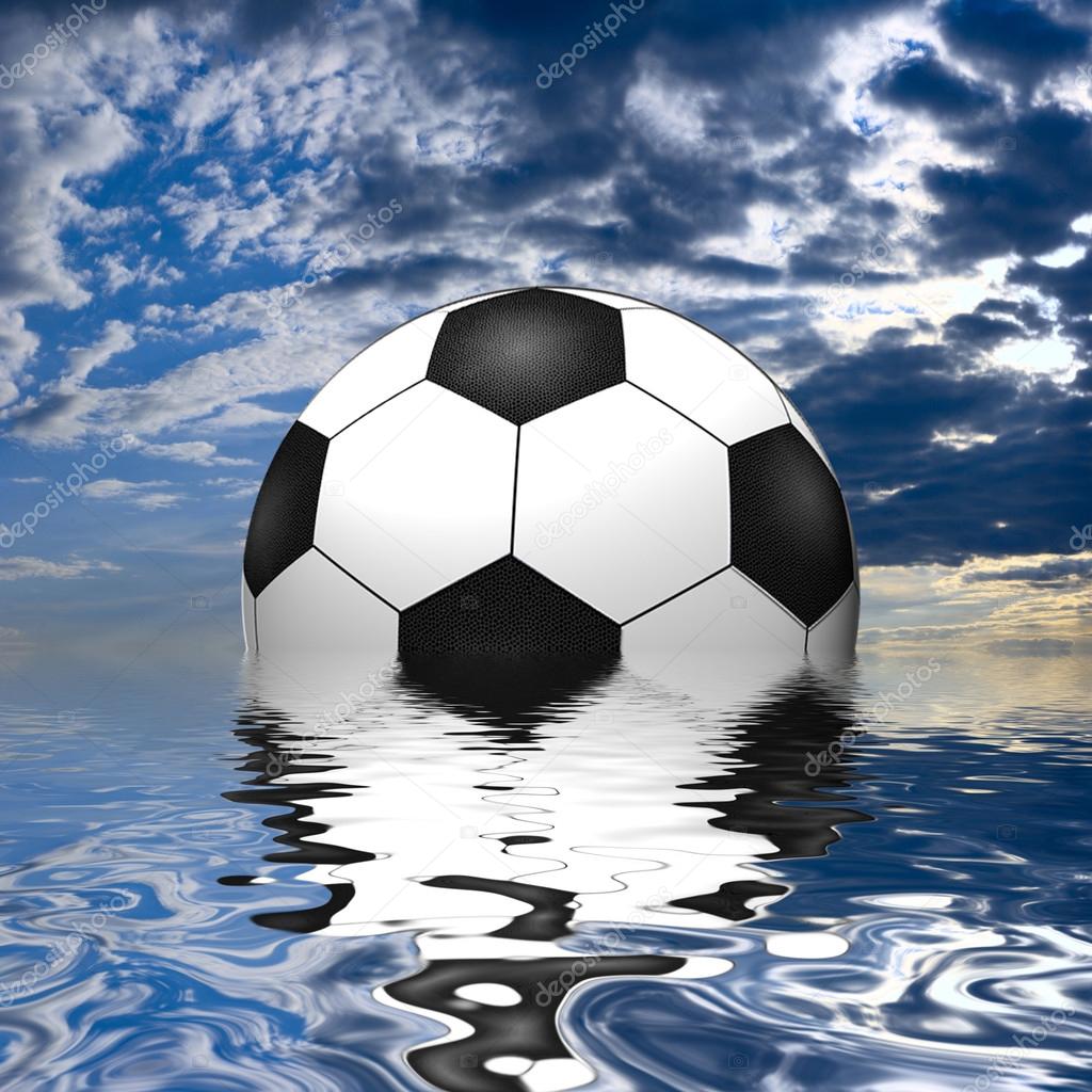 Soccer ball reflected in water over the blue sky with clouds