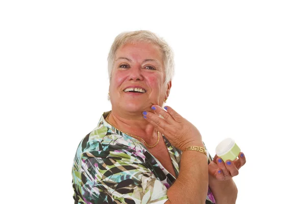 Senior mulher aplicando loção em seu rosto — Fotografia de Stock