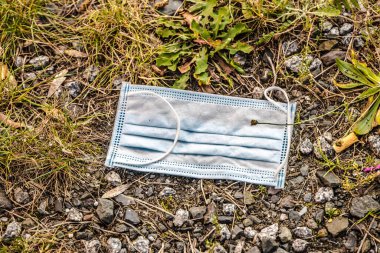 Kaldırımda tıbbi maske. Kullanılmış bir maskeyi sokağa atmak yanlıştır..