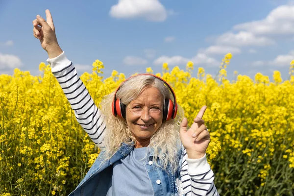 Mujer Mayor Escuchar Música Con Auriculares Campo Canola Floreciente — Foto de Stock