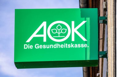 GERMANY, DILLENBURG 2022-07-17: Green AOK Sign hanging on a old House Facade. AOK is a german health insurance.