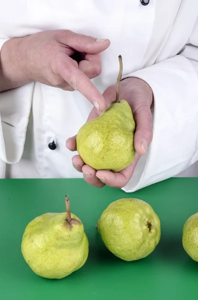 Female chef shows with her index finger on a pear — Stock Photo, Image