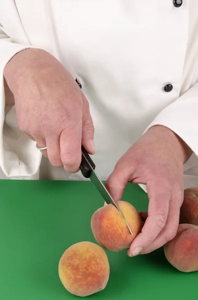 Vrouwelijke chef-kok een perzik voorbereiden — Stockfoto