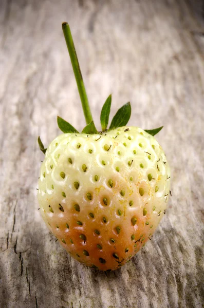 Unripe strawberry on a wooden board — Stock Photo, Image
