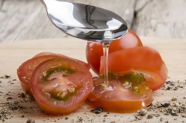Oil flows from a spoon on cherry tomatoes — Stock Photo, Image