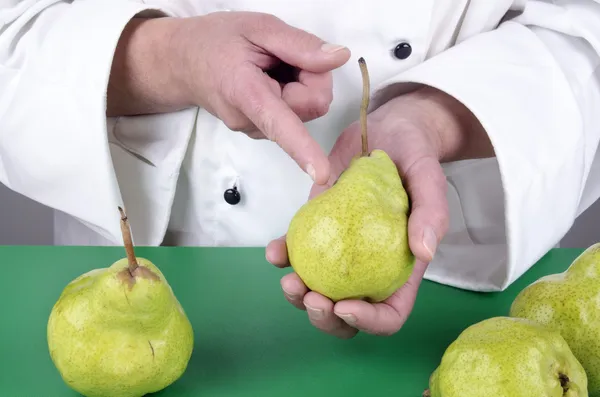 Female chef shows with her index finger on a pear — Stock Photo, Image