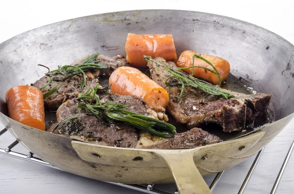 Lamb chops and carrots in a brass pan — Stock Photo, Image