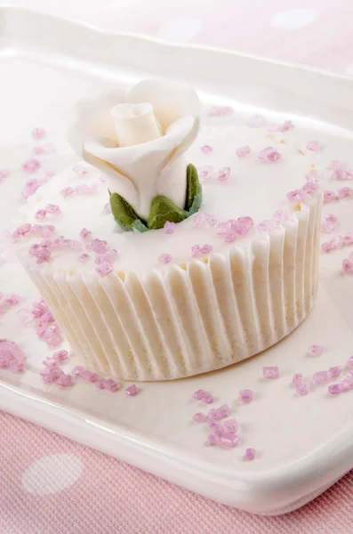 Кекс с белой розой и розовыми брызгами — стоковое фото