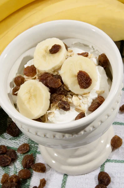 Iogurte com passas e fatias de banana — Fotografia de Stock