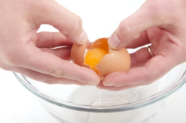 Open egg over a glass bowl — Stock Photo, Image