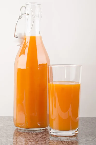 Suco de cenoura em um copo e uma garrafa — Fotografia de Stock